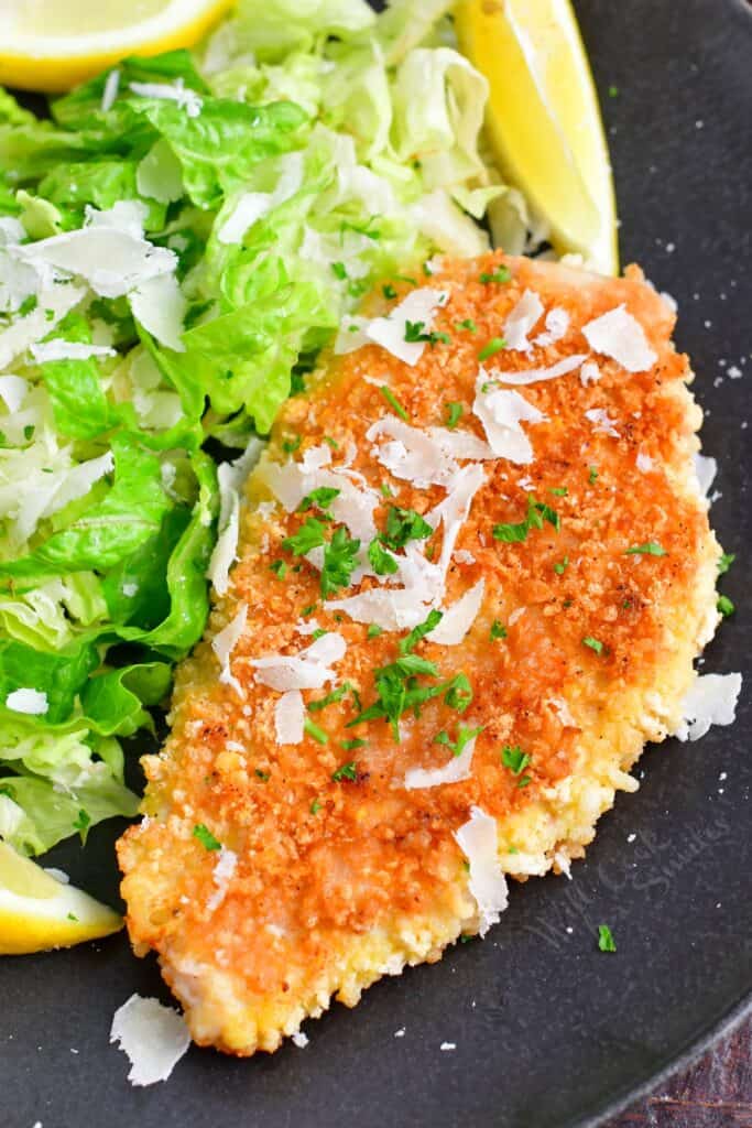 Chicken milanese is served with a side salad. 
