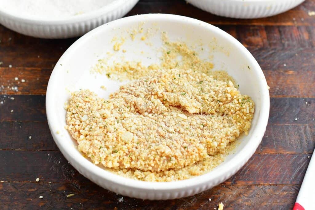 breaded uncooked chicken in a white bowl