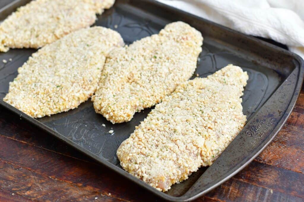 breaded chicken breasts on a metal sheet tray