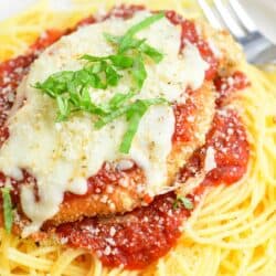 spaghetti topped of with marinara sauce and chicken parmesan