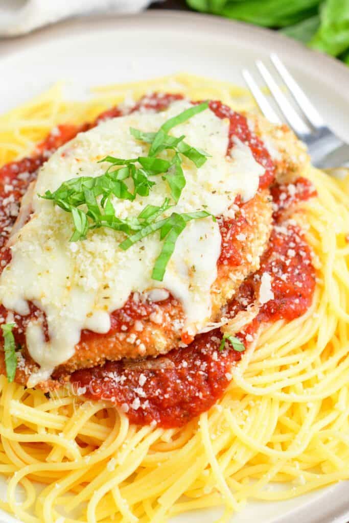 spaghetti topped of with marinara sauce and chicken parmesan
