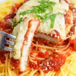 chicken parmesan on top of spaghetti with a sliced cut off