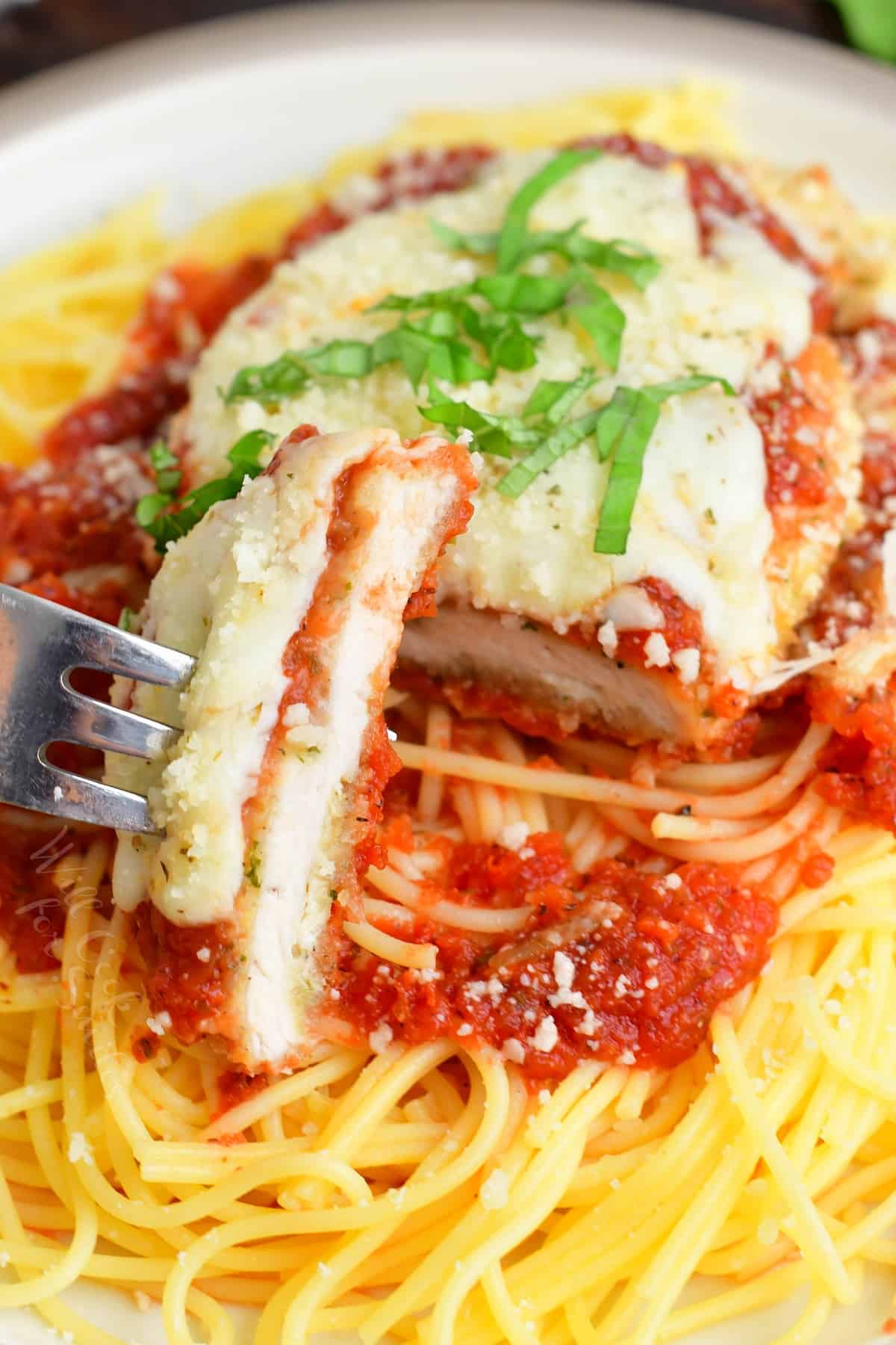 chicken parmesan on top of spaghetti with a sliced cut off