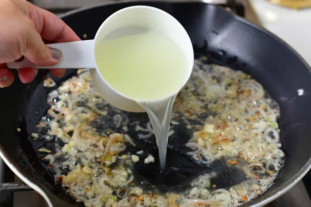 adding pasta cooking water to the pan with onions