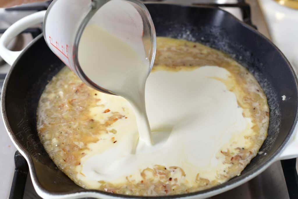 adding heavy cream to the sauce in a pan