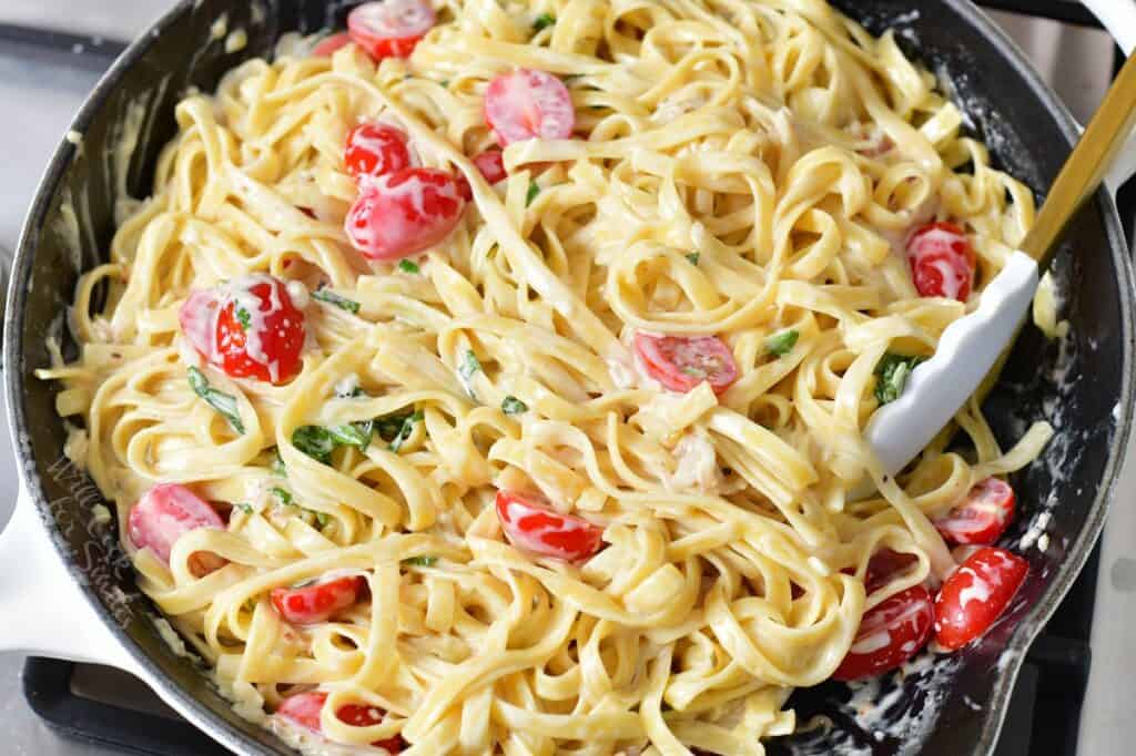 tossed fettuccine tomatoes and basil in parmesan cream sauce in a pan