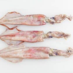 three whole squid on a cutting board