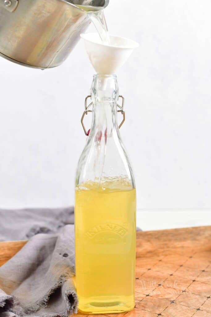 Limoncello is being carefully poured from the pot into a bottle.
