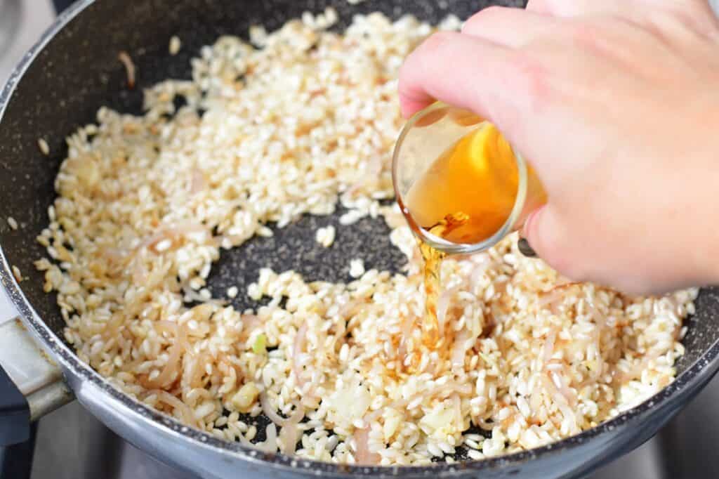 adding sherry to the rice in the pan