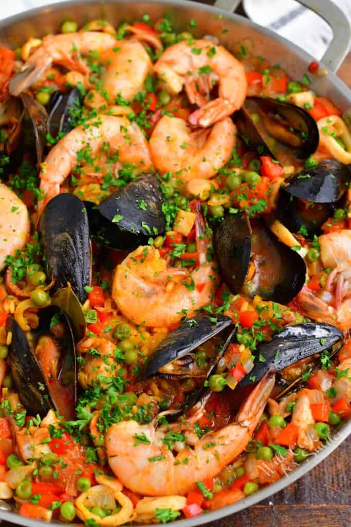 A metal pot is filled with paella. 