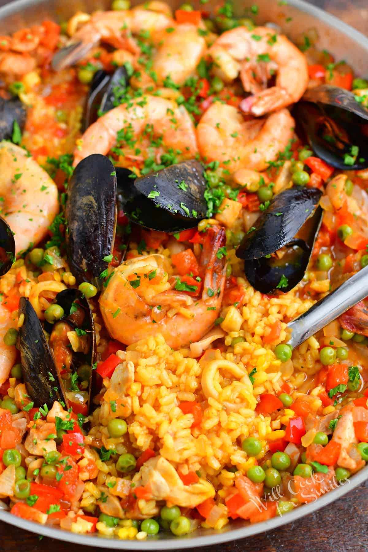 A serving spoon is in the process of removing a serving of paella from the pan. 