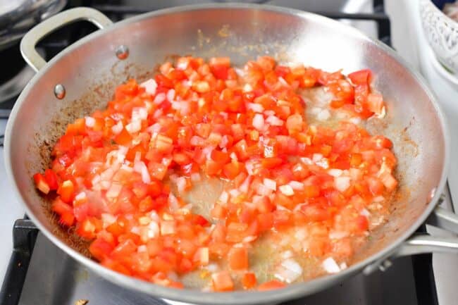 Diced tomatoes are being cooked in a pan. 
