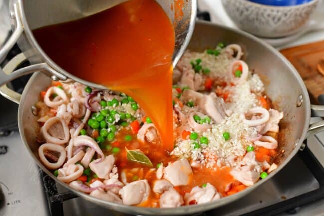 Chicken stock is being poured into a full pan. 