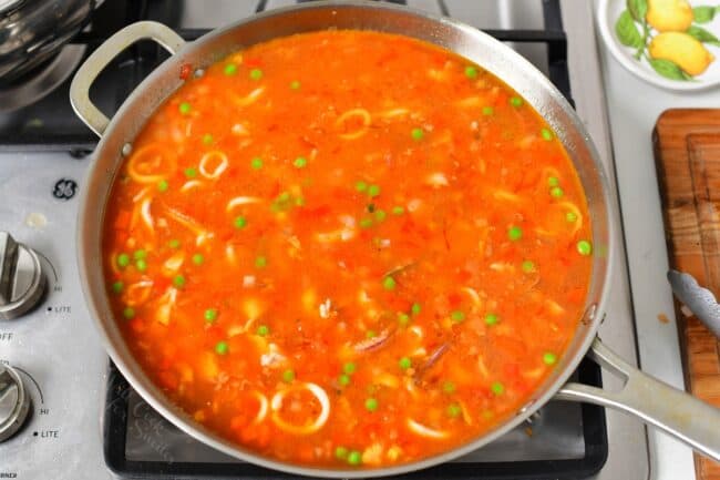 Paella is cooking on a stovetop. 