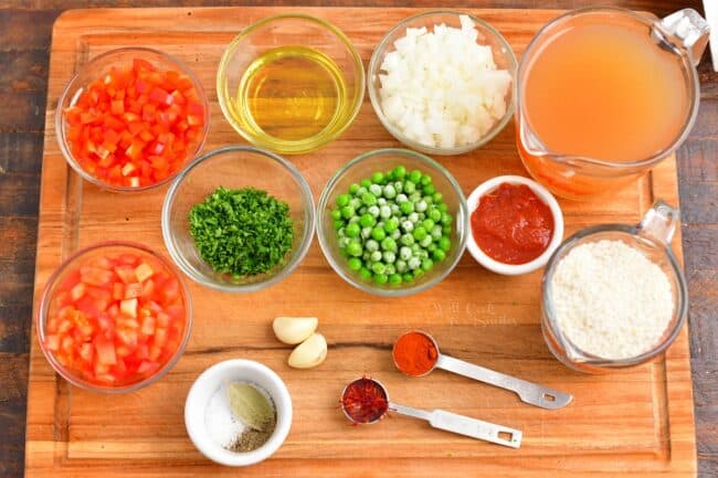 The ingredients for paella are placed on a wooden cutting board. 