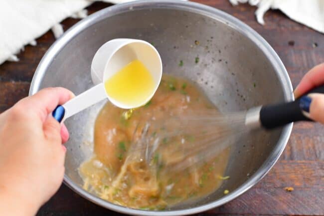 adding oil into the vinaigrette while whisking