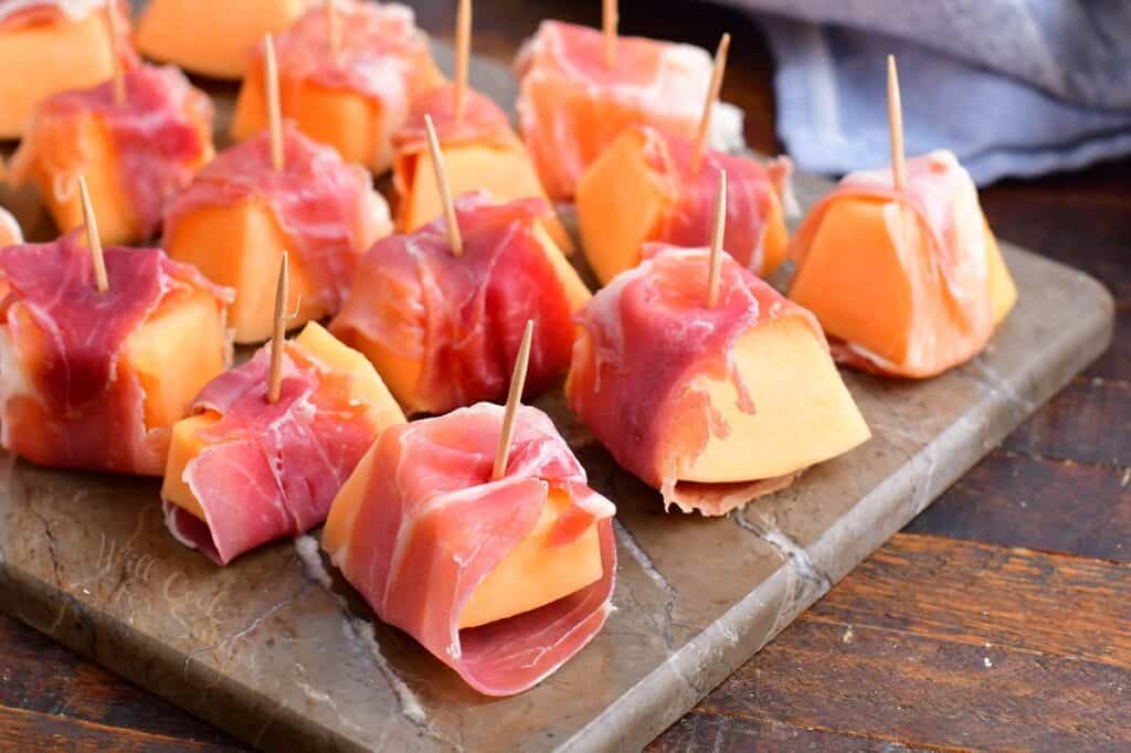 pieces of cantaloupe wrapped in prosciutto with a toothpick