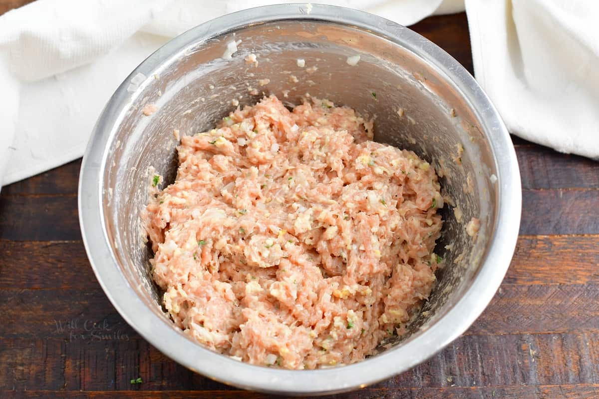 mixed ingredients for chicken burgers in a metal mixing bowl.