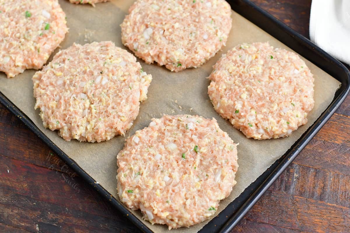 several shaped chicken burger patties in a tray.