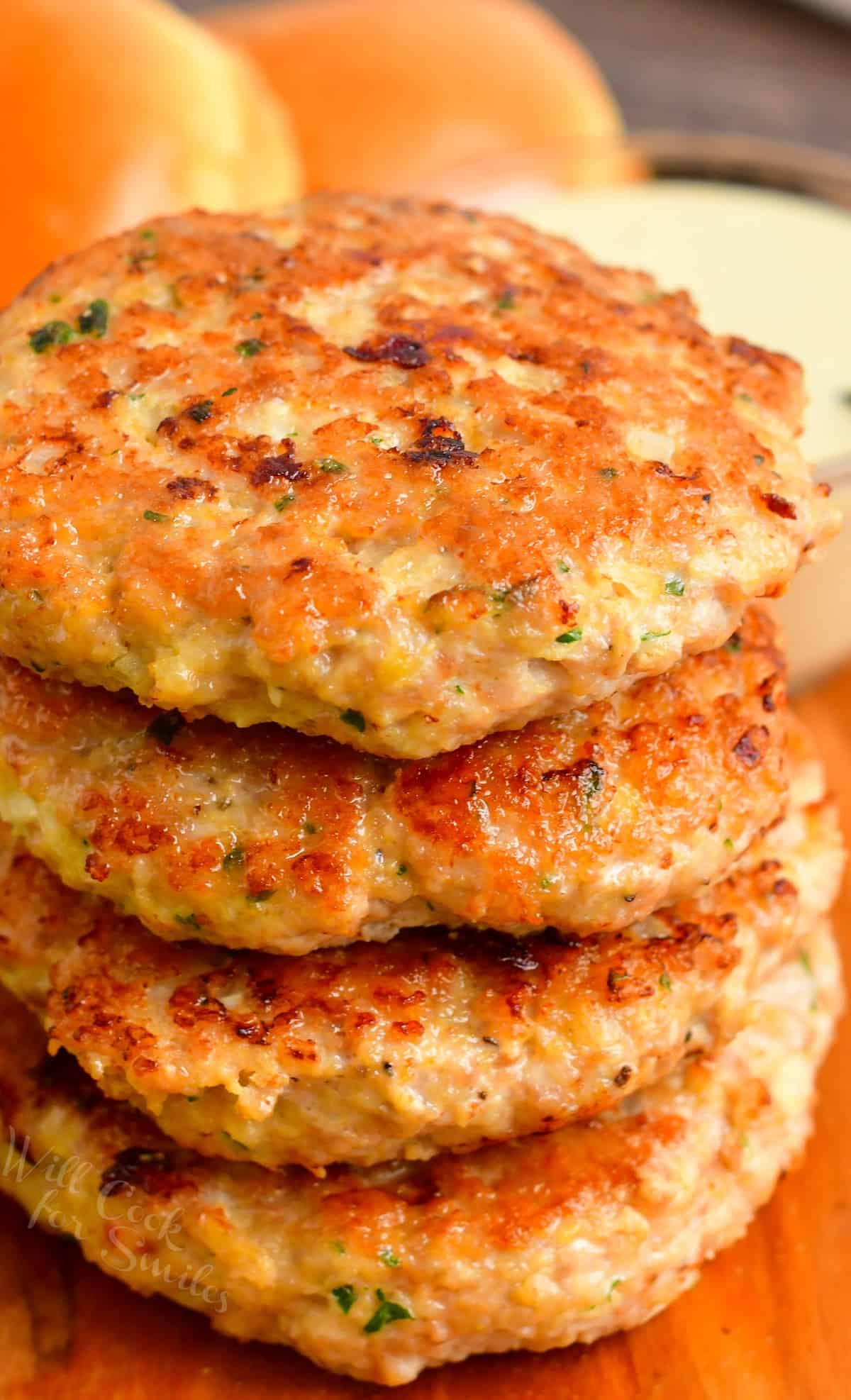 four juicy chicken burger patties stacked on top of each other.