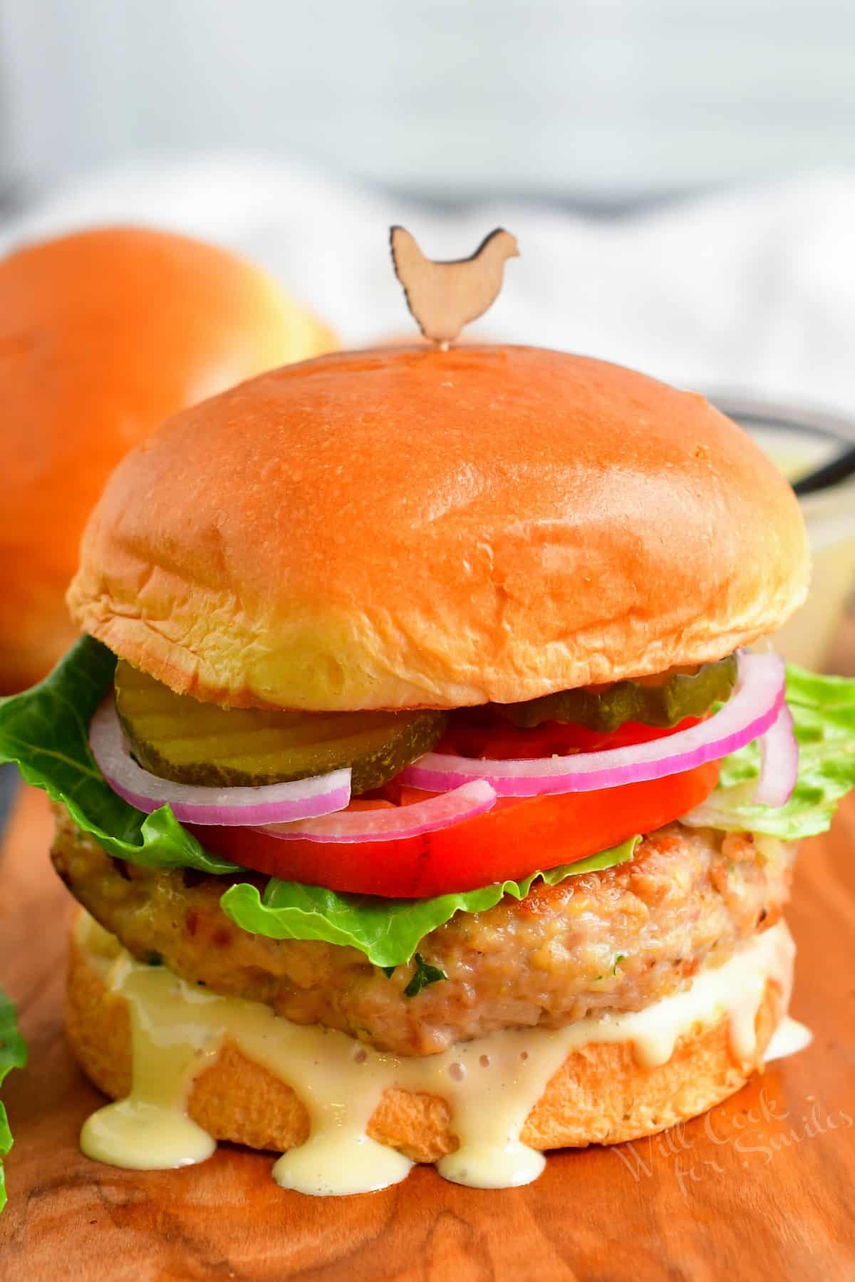 Juicy chicken burger on Brioche bun with creamy sauce dripping and vegetable toppings.