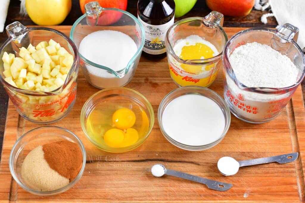 The ingredients for apple bread are placed on a wooden cutting board. 