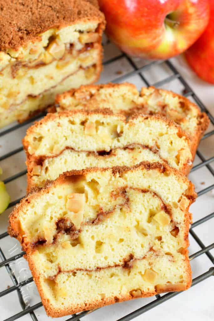 Four slices of apple bread are lined up on a wire cooling rack.