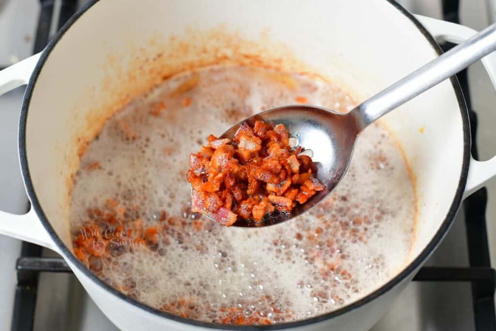scooping bacon bits out of the Dutch oven with metal spoon