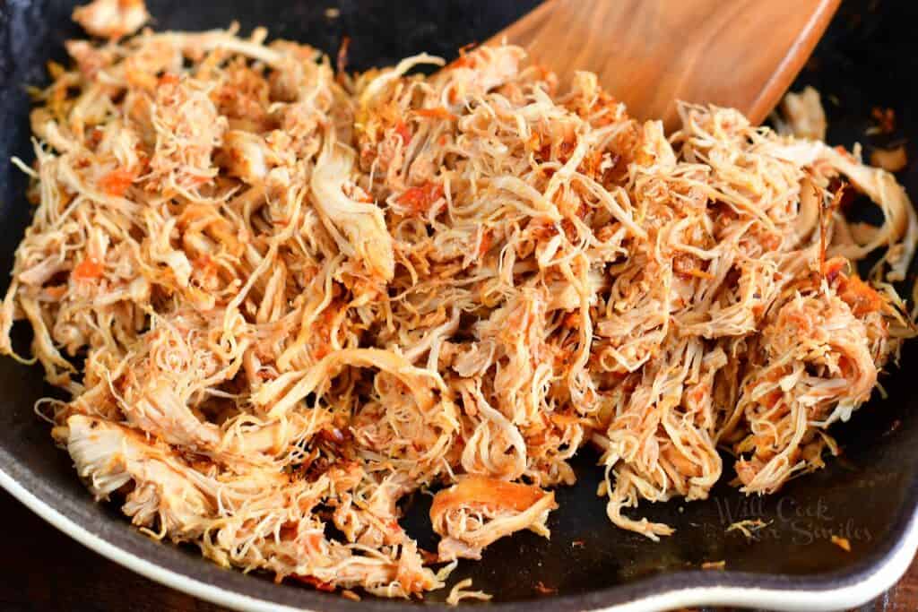 searing shredded chicken in a pan