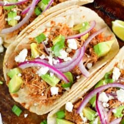 top view of the chicken tacos in a shell topped with onions and avocado