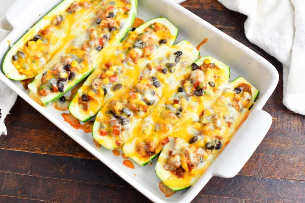 cooked zucchini boats in a white baking dish