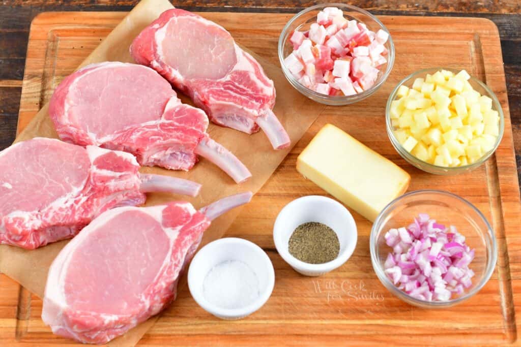 The ingredients for stuffed pork chops are placed on a wooden cutting board. 