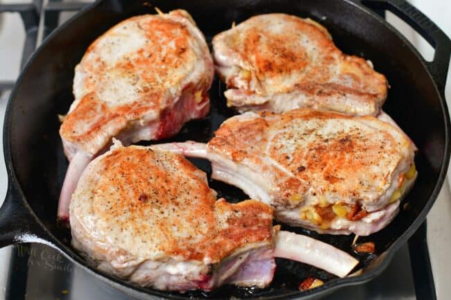 Pork chops are browning as they cook in a pan.