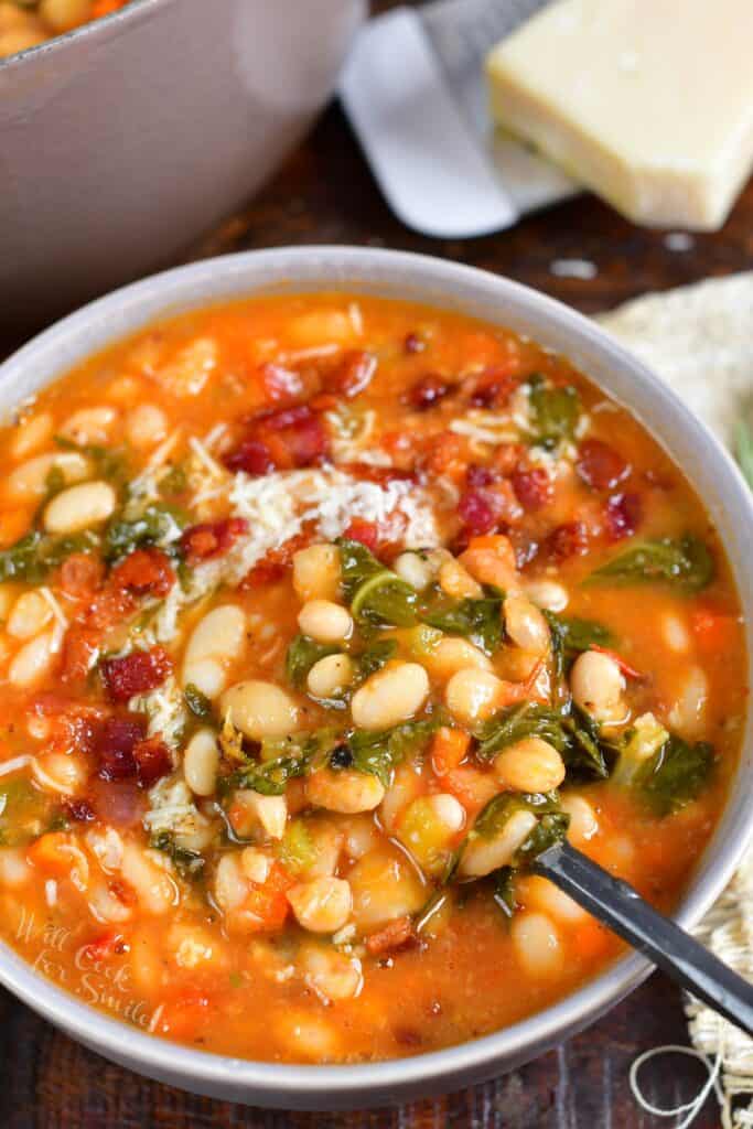 A bowl of white bean soup is presented with a spoon on a countertop. 