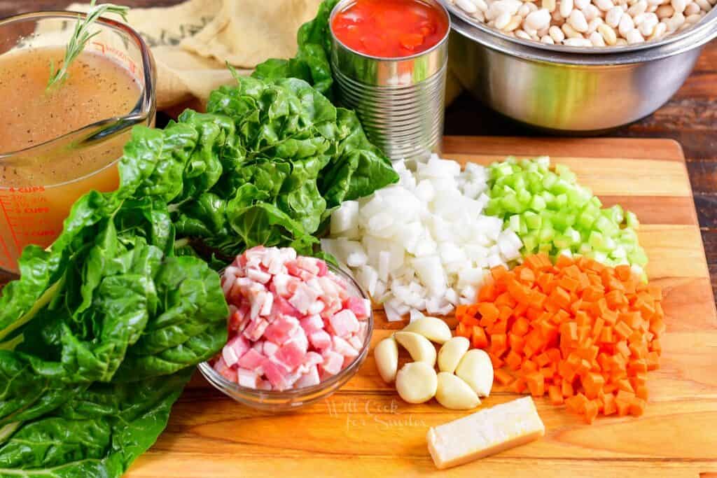 The ingredients for white bean soup are presented on a wooden cutting board. 