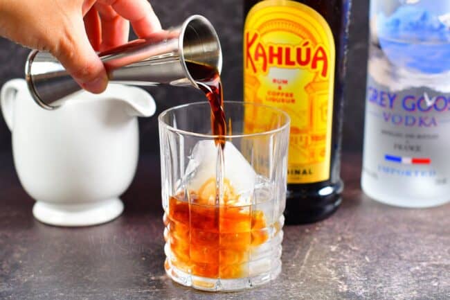 Adding Kahlua to the glass with vodka and ice