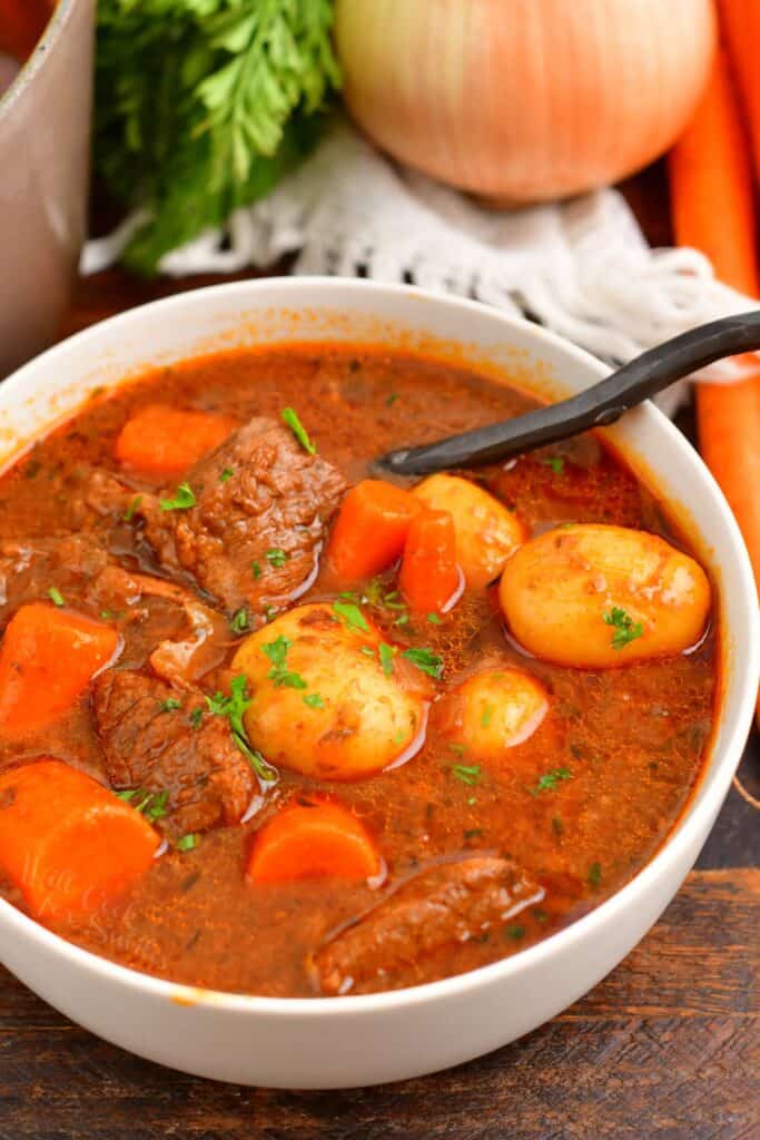 beef stew in a white bowl with a spoon in it