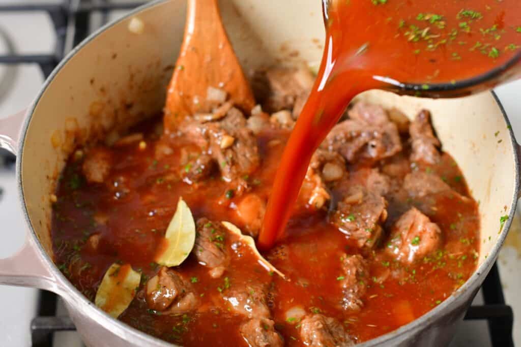 adding the broth mixture to the beef in a Dutch oven