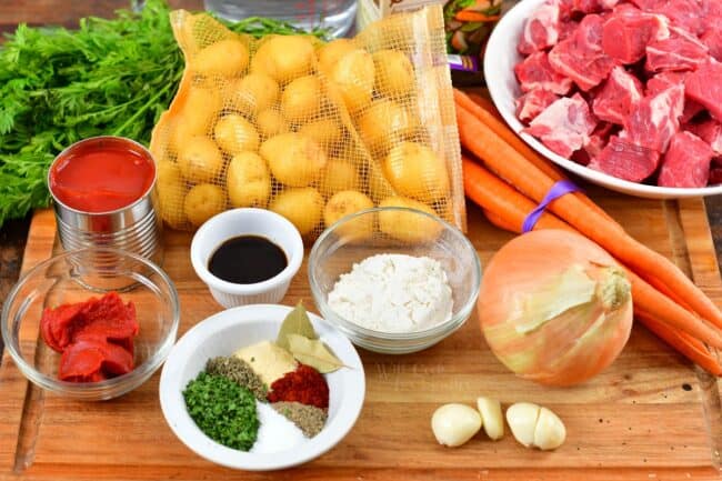 ingredients to make beef stew on a cutting board