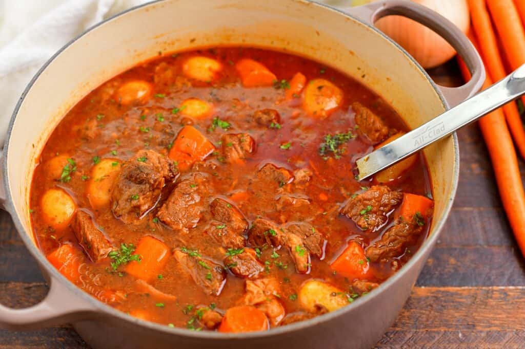 closeup of beef stew in a large pot with a ladle in it