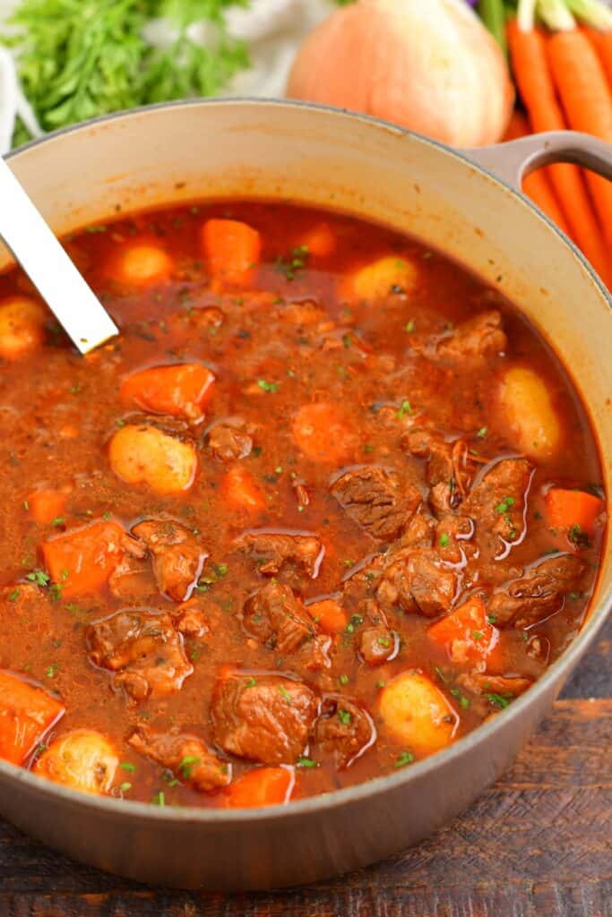 top view beef stew in a pot with vegetables around the pot