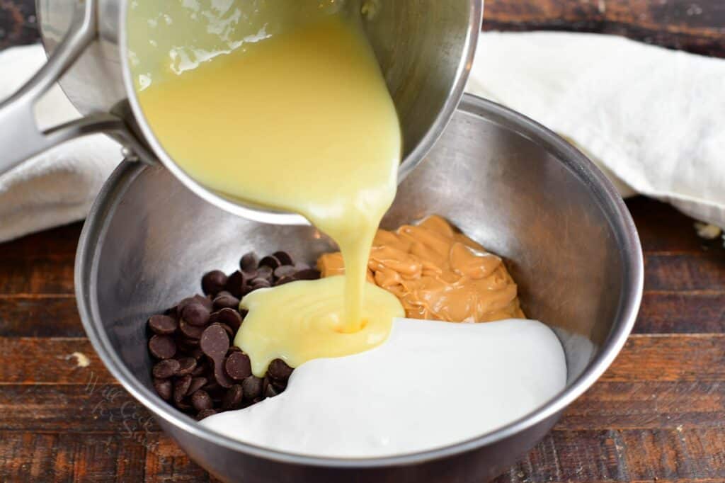 adding sweetened condensed milk into the mixing bowl with other fudge ingredients