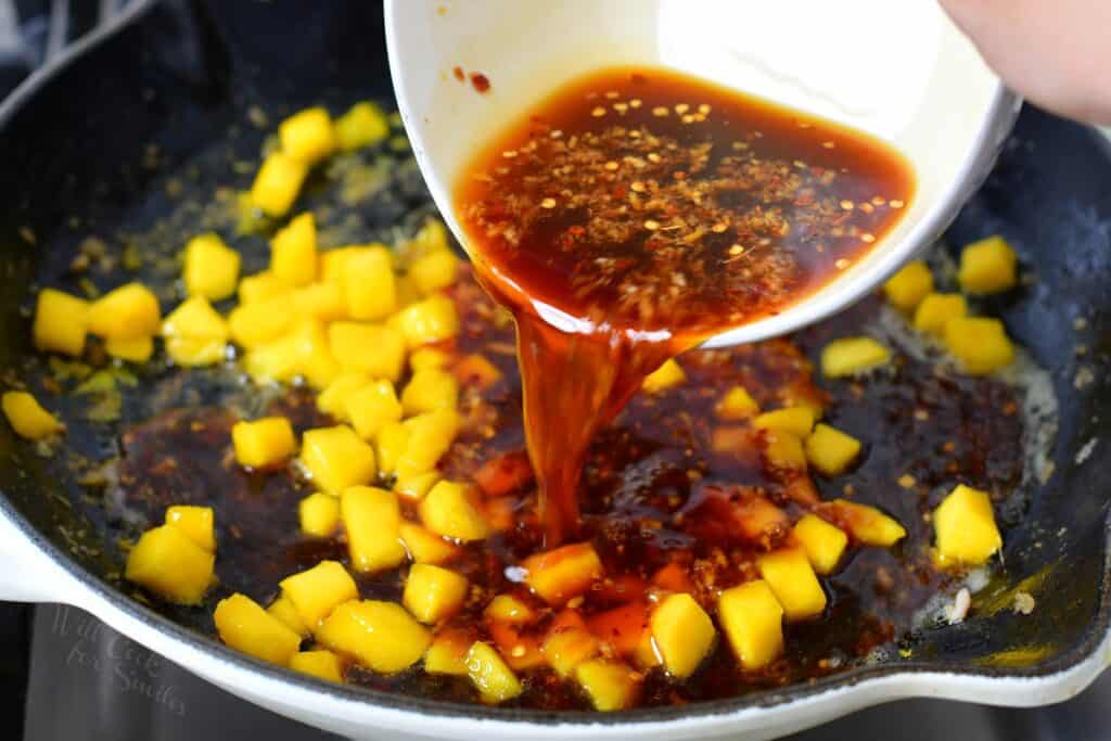 adding soy sauce mixture to the mango in a pan