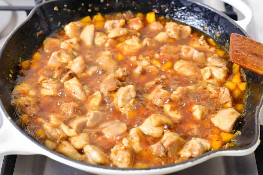 adding chicken to the sauce and cooking in a pan