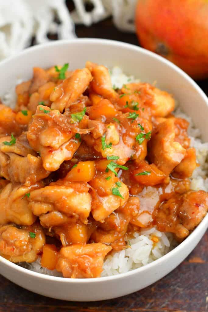 cooked mango chicken over rice in a white bowl