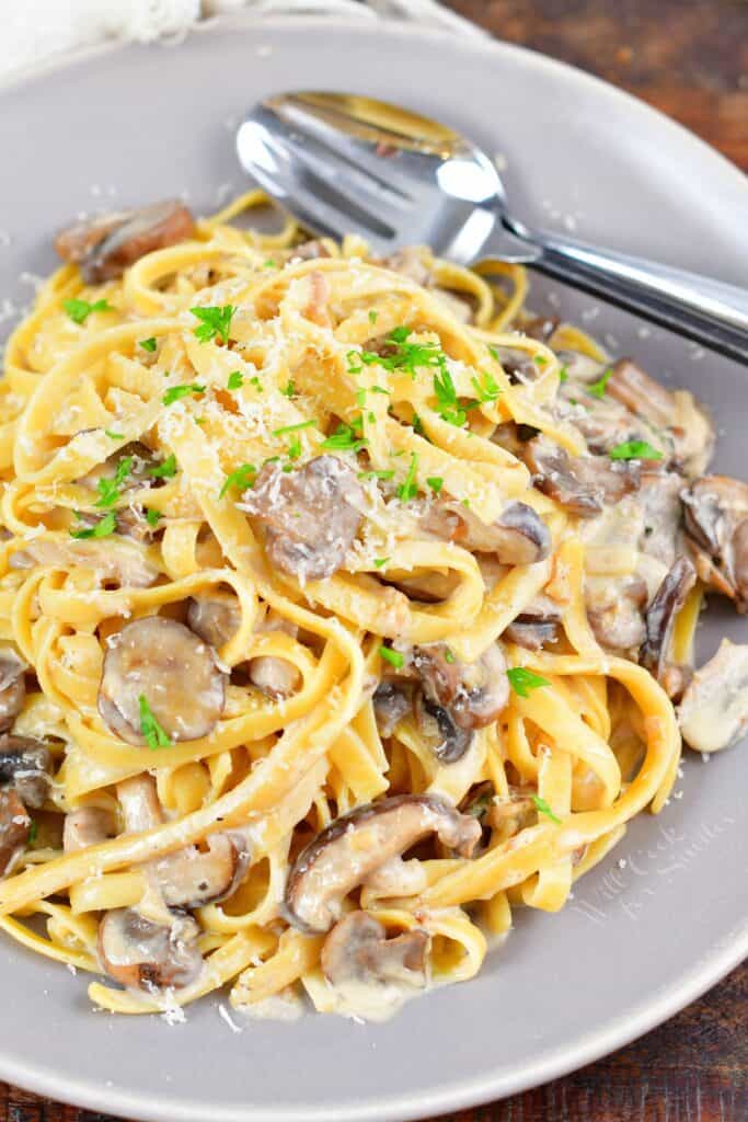 top view of pasta tossed in creamy mushroom sauce on grey plate