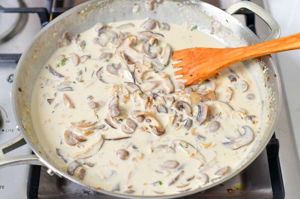 creamy mushroom sauce in a pan with a wooden spatula