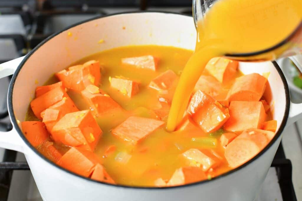 adding vegetable broth to the pot of sweet potatoes