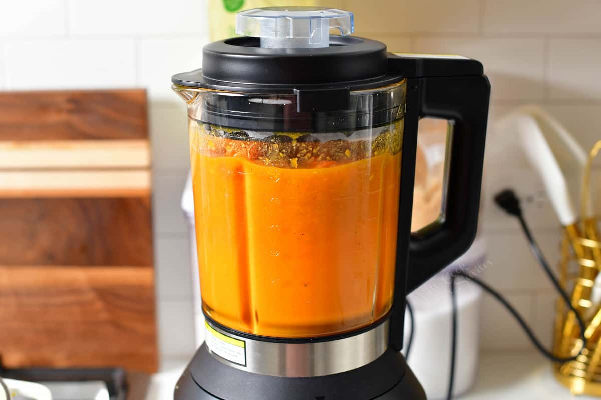 blending bright orange soup in a blender.