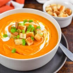 sweet potato soup in a bowl with croutons on top and next to the bowl